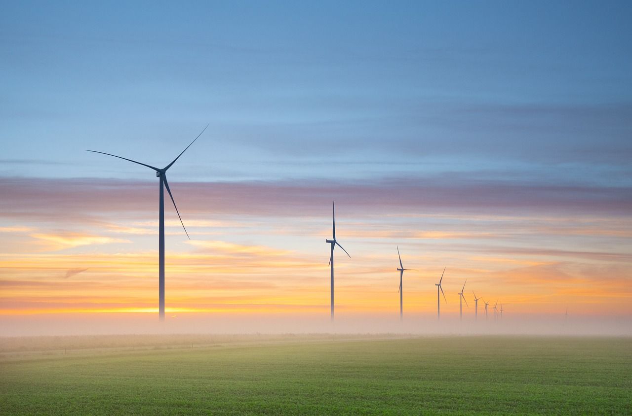 Éoliennes au lever du soleil dans la brume.